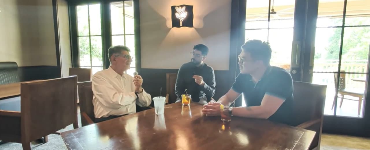 Three people talking around a restaurant table during a podcast recording